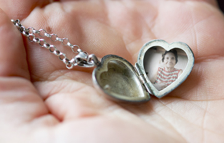Silver heart-shaped photograph locket held in hand