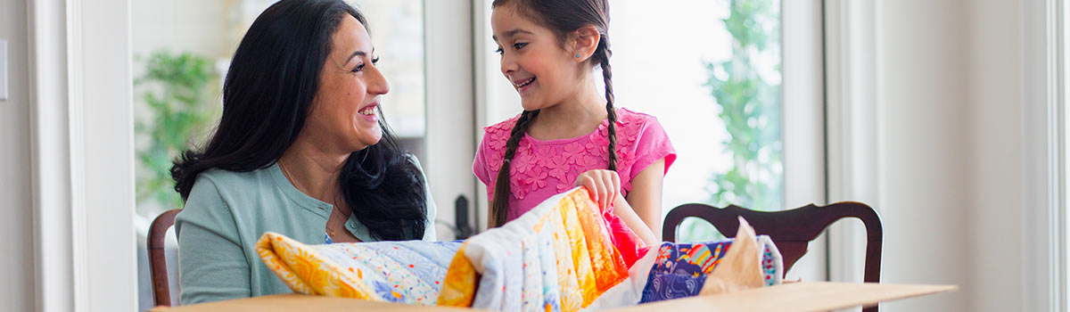 Mother and daughter opening a shipping box with a quilt inside