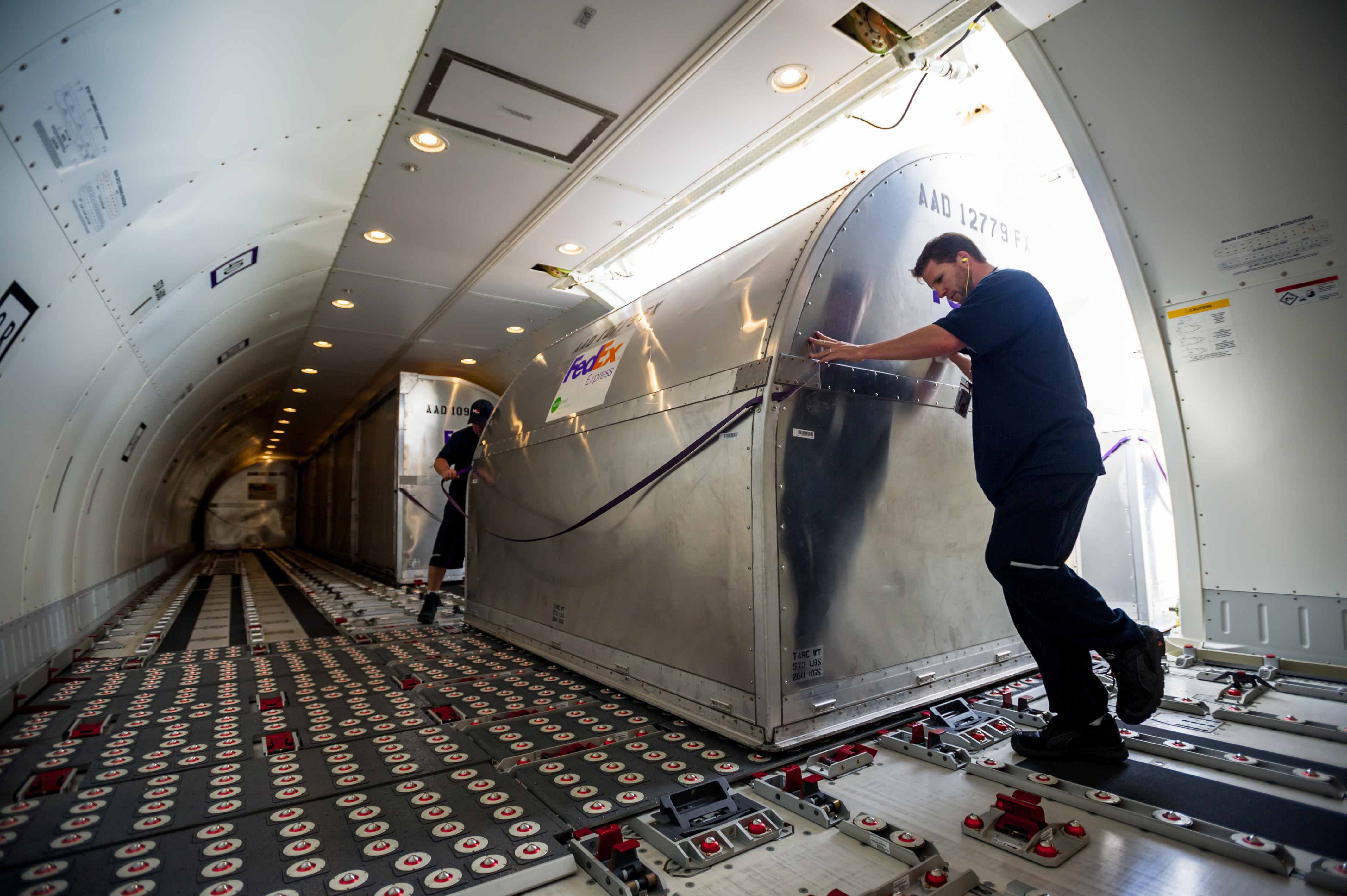 A courier loads packages onto a FedEx cargo plane