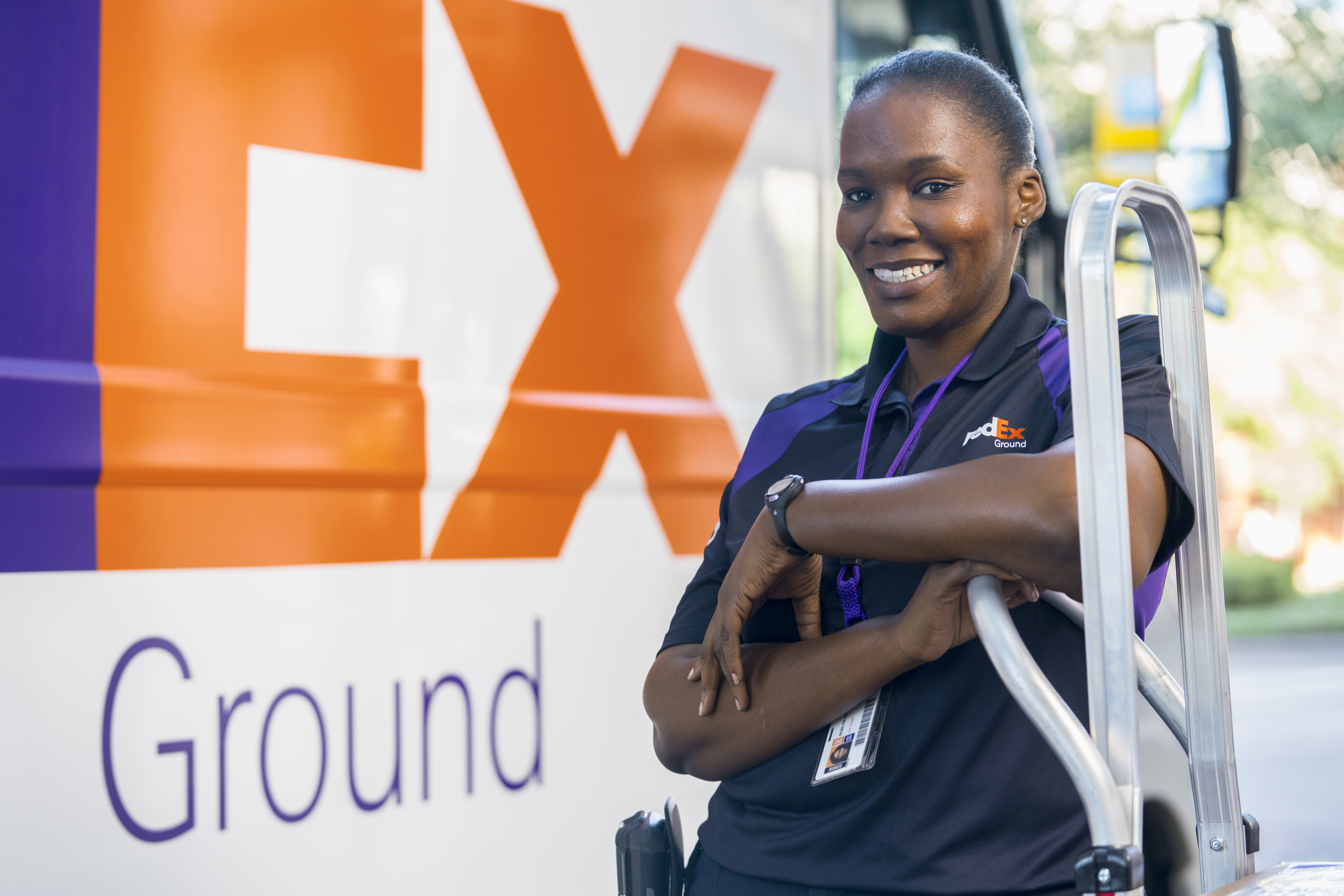 A FedEx delivery driver standing next to a truck