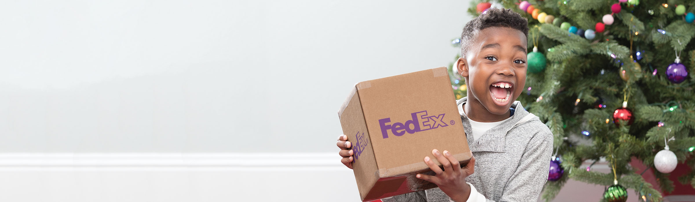 A child holding a FedEx brown box at Christmas