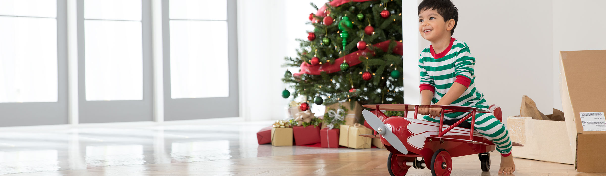 A little boy riding a toy plane at Christmas
