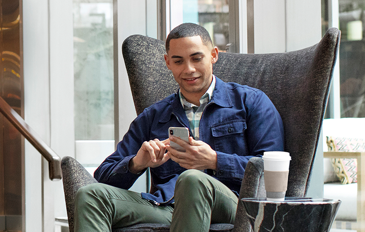 A man sitting in a lobby using a smart phone