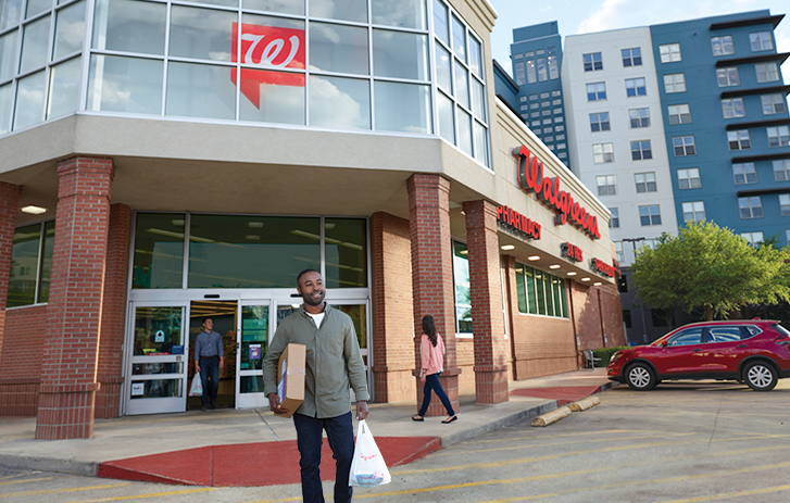Man entering a Walgreens location with a FedEx package in hand.