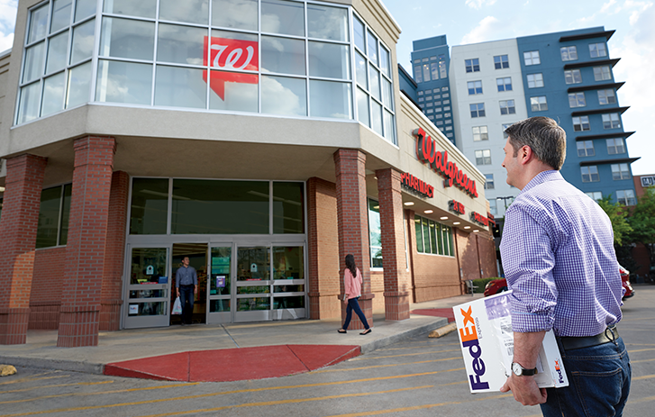 Man walking towards a Walgreens location with a white FedEx box