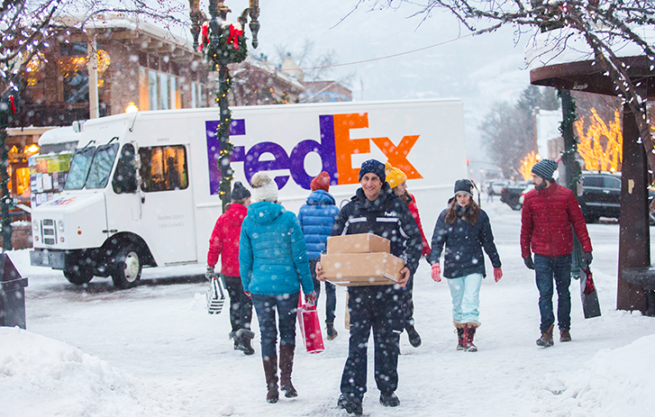 A FedEx driver delivering boxes in the snow