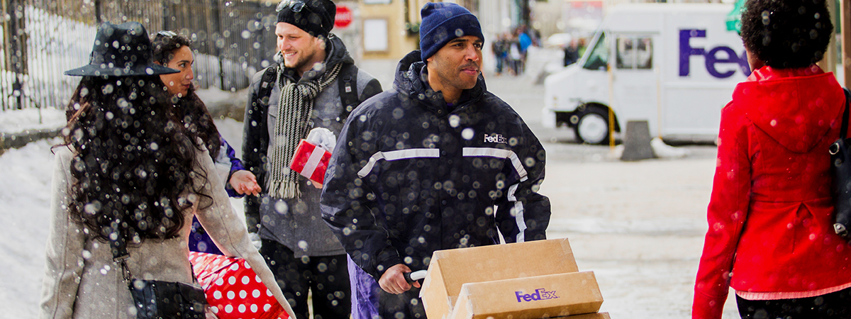 fedex delivery driver pushing packages on snowy sidewalk