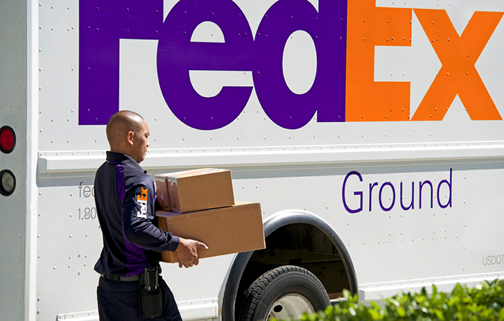 FedEx delivery truck driving by Christmas tree