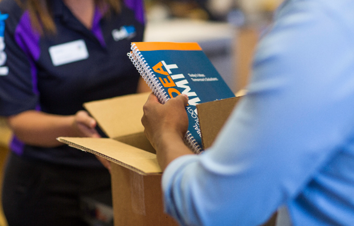 Business person pulling printed materials from shipping box