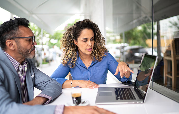 Businesswoman and businessman working together on laptop
