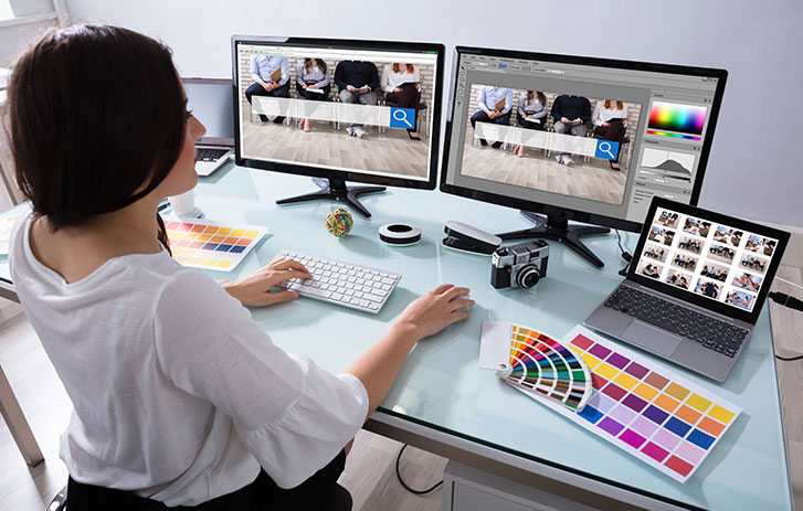 Female designing on multiple computer monitors