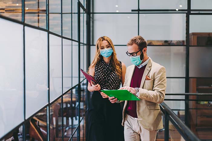 Two masked office workers with clipboards
