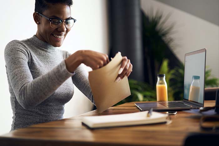 Woman opening envelope at home desk