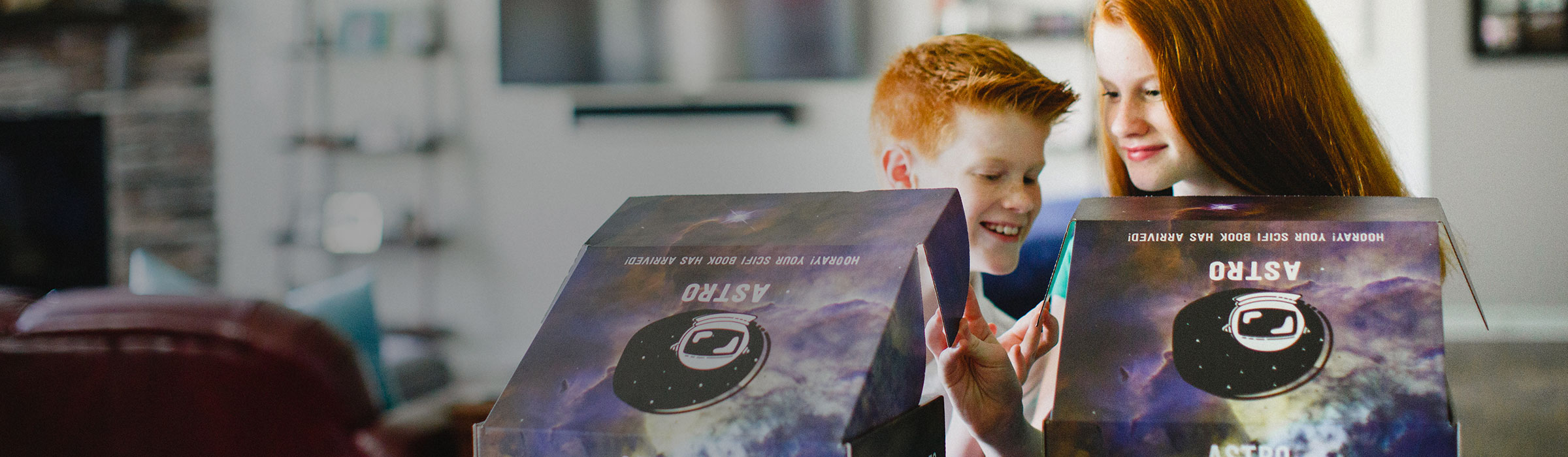 Two children opening custom branded graphic boxes with a outer space theme