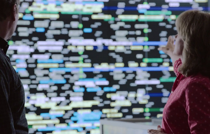 two people in a control center looking at a wall of data