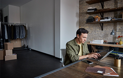 A clothing store owner uses his laptop to check FedEx Ship Manager Server.