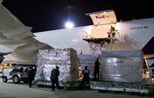 Employees loading freight packaging into plane