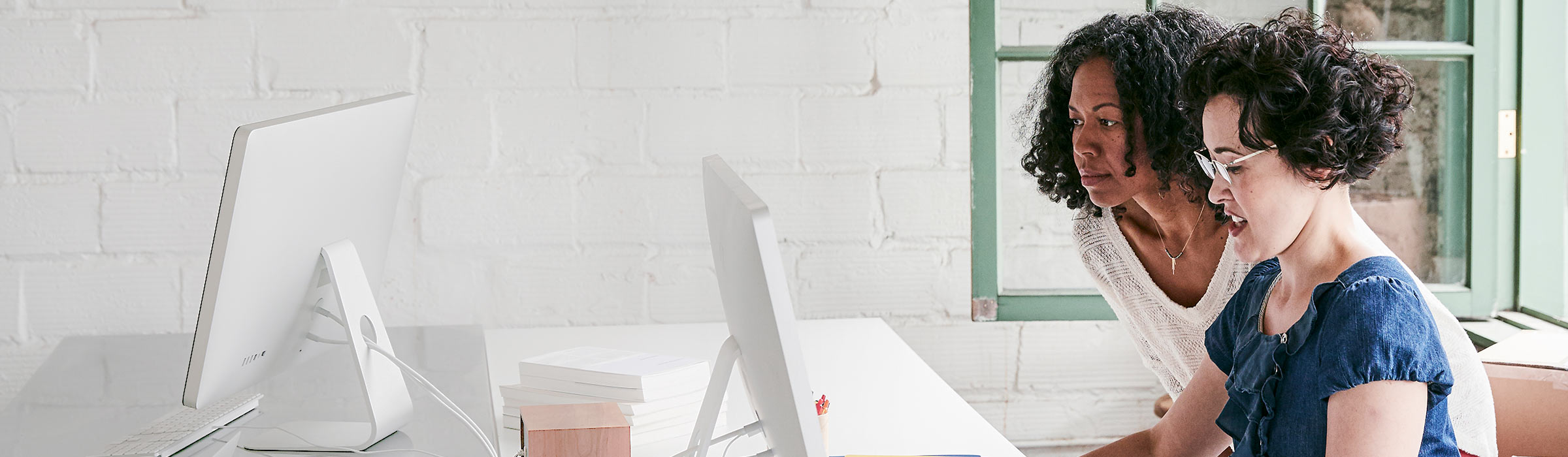 Two women at desk looking at computer