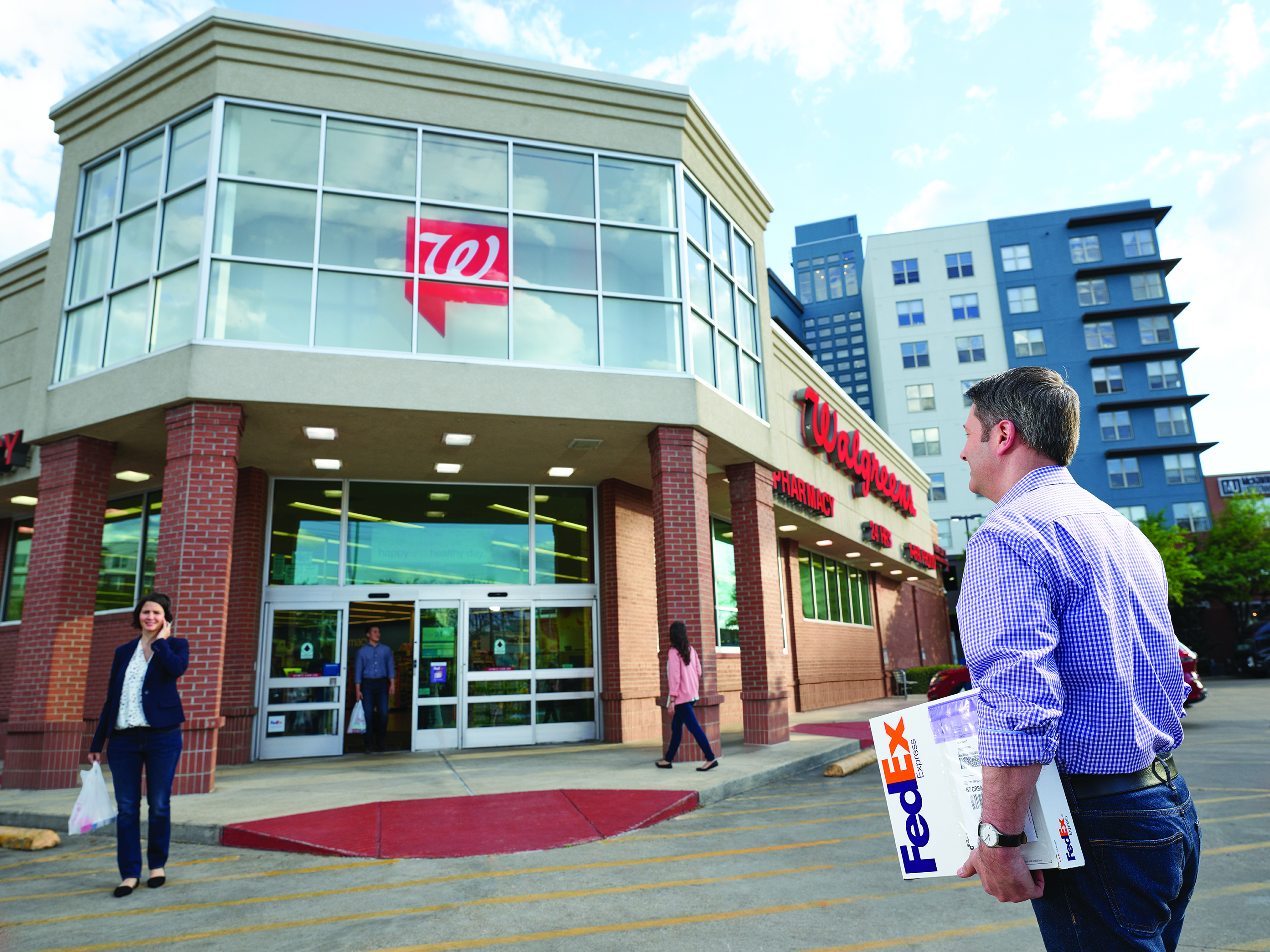 A man walks toward a Walgreens with a FedEx package to drop off