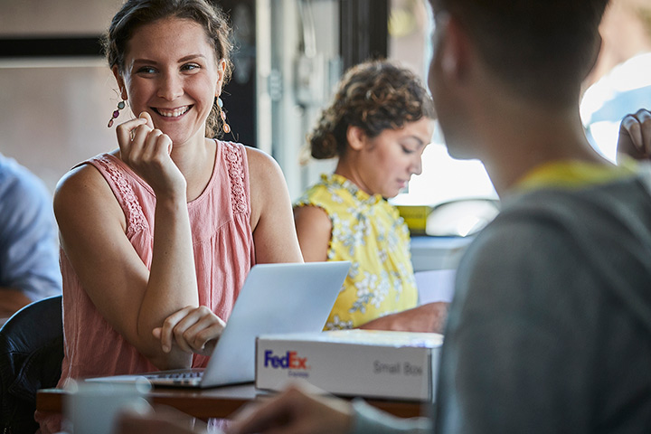 Woman with laptop smiling in café setting