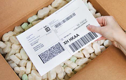 A woman pulls a packing slip from a FedEx box.