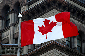 Low-angle view of Canadian flag flying over a clock tower in Victoria Park; Kitchener, Ontario