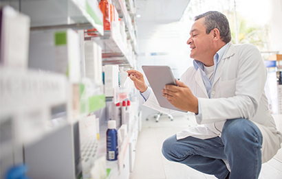 FedEx Temp Assure packages sit in the foreground; a pharmacist stocks a shelf in the background.