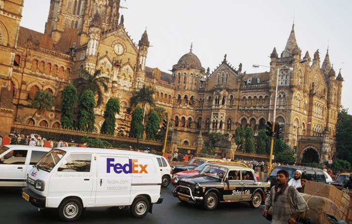 FedEx delivery vans park in front of a European cathedral.