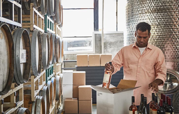 A photo of a man packing wine to be shipped