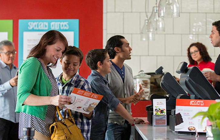 A visual of a family ordering at a restaurant counter check out.
