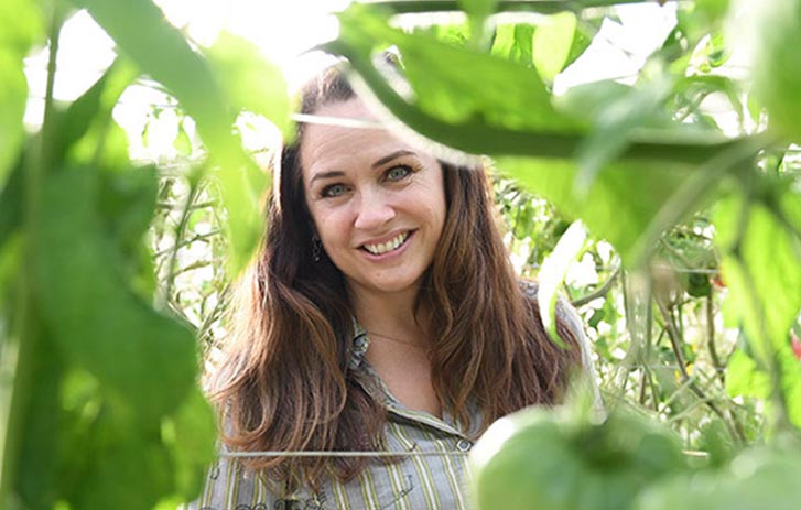 A photo of Gina Stryker, owner of Gina Cucina, in a tomato garden.