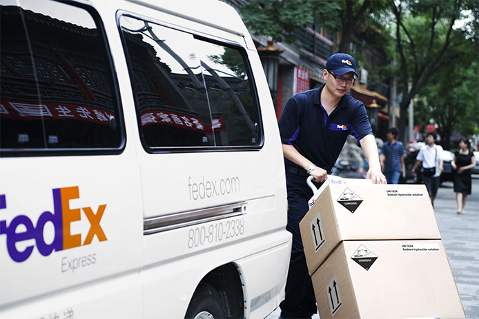 courier delivering dangerous goods packages on street near FedEx Express vehicle