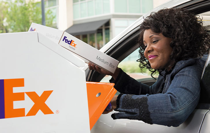 woman putting fedex medium box in drop box