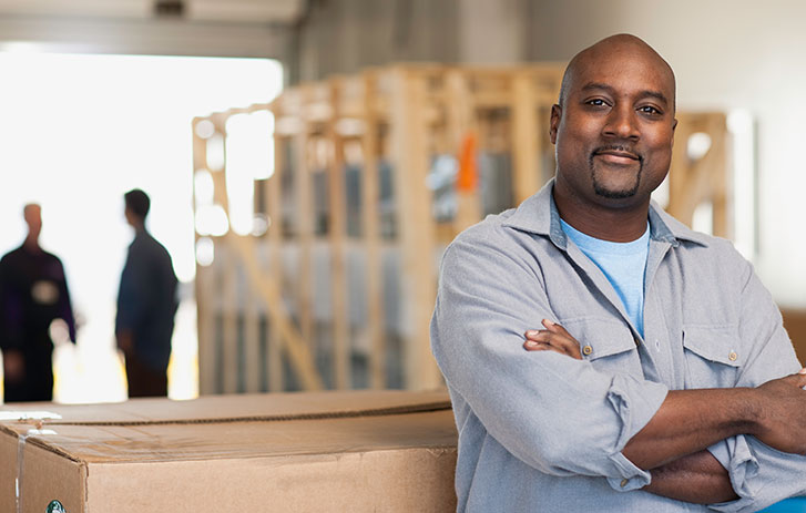 man leaning on large box in warehouse