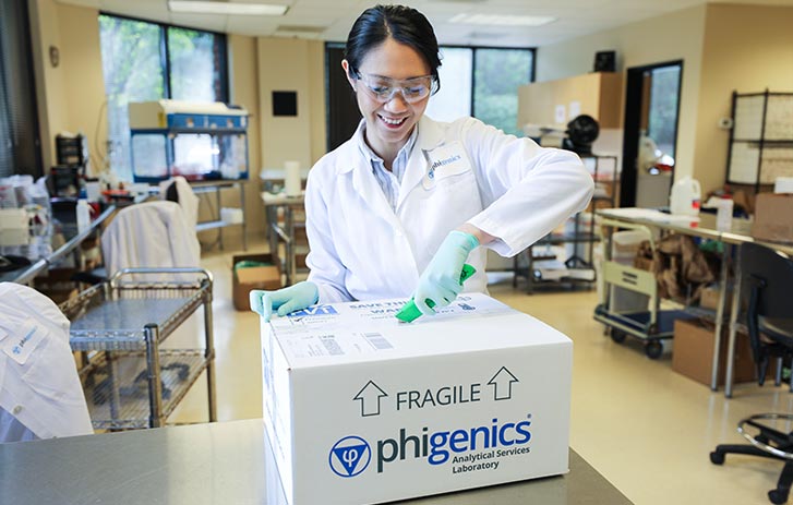 A photo of a woman in a white lab coat opening a custom Phigenics package