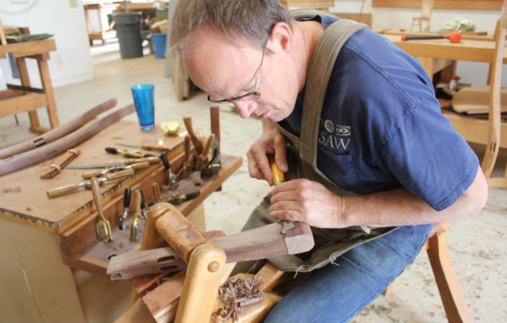 A photo of Brian Boggs in his workshop crafting a wooden chair