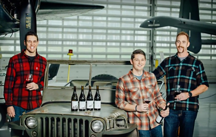 A photo of Ben Martin, Paul Warmbier, and Ryan Mills from Dauntless Wine Company holding glasses and bottles of their wine