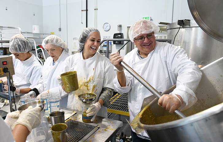 A photo of a group of people in a kitchen jarring food