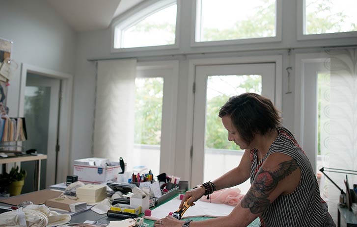 A photo of a woman cutting fabric in her office