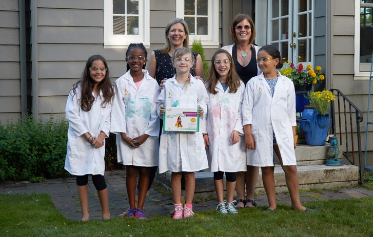 A photo of Marcie Colledge and Kelly McCollum and a group of girls wearing lab coats