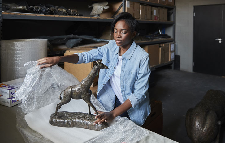 A photo of a woman packing a small statue in a special wrap so that it won't break