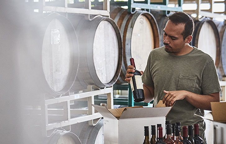 hombre empacando botellas de vino para enviarlas