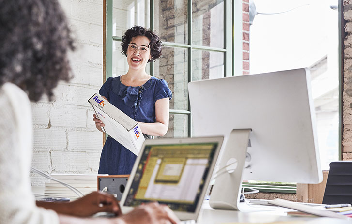 smiling woman holding fedex package in office