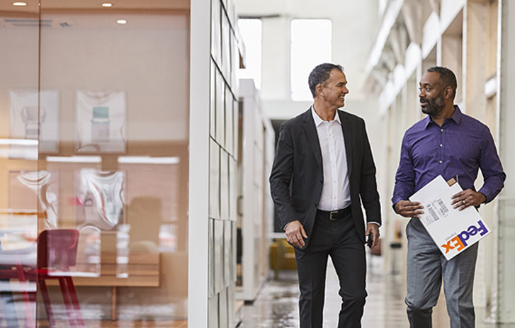 man holding fedex envelope while talking to coworker in office