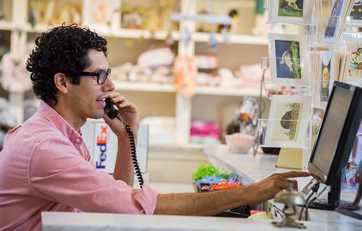 man talking on phone and looking at a computer