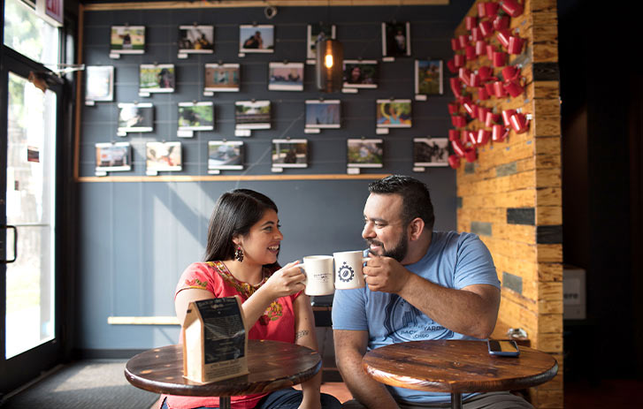 Back of the Yards Coffee Co. A photo of 2018 grant winners from Back of the Yards Coffee Co. sitting at a table in their coffeehouse with coffee mugs lifted in celebration