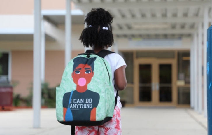 A photo of a girl standing outside of a school with a Blended Designs backpack