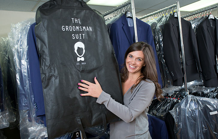 A photo of Diana Ganz from The Groomsman Suit surrounded by an inventory of suits