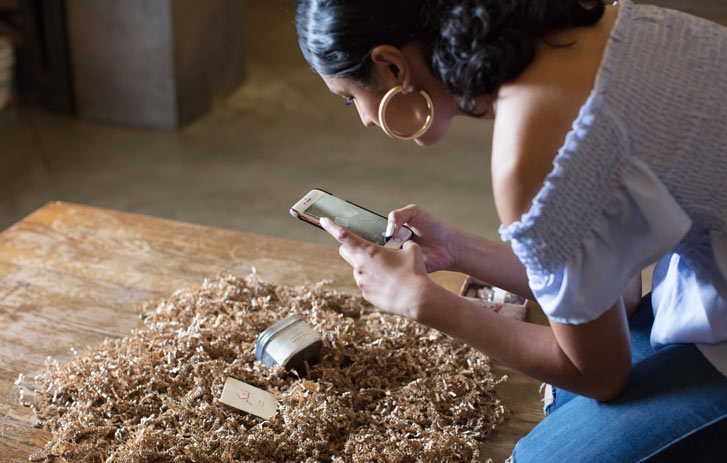 A photo of a woman taking a photo of her product using her cell phone