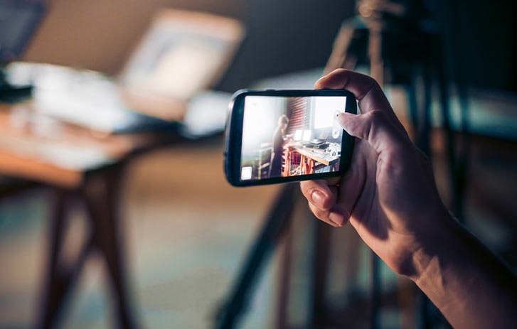 Make a brand video A photo of a person using their cell phone to record a video